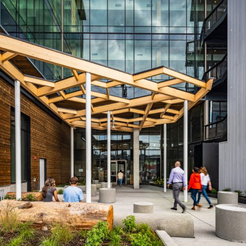 People walking under wood pergola at building entry