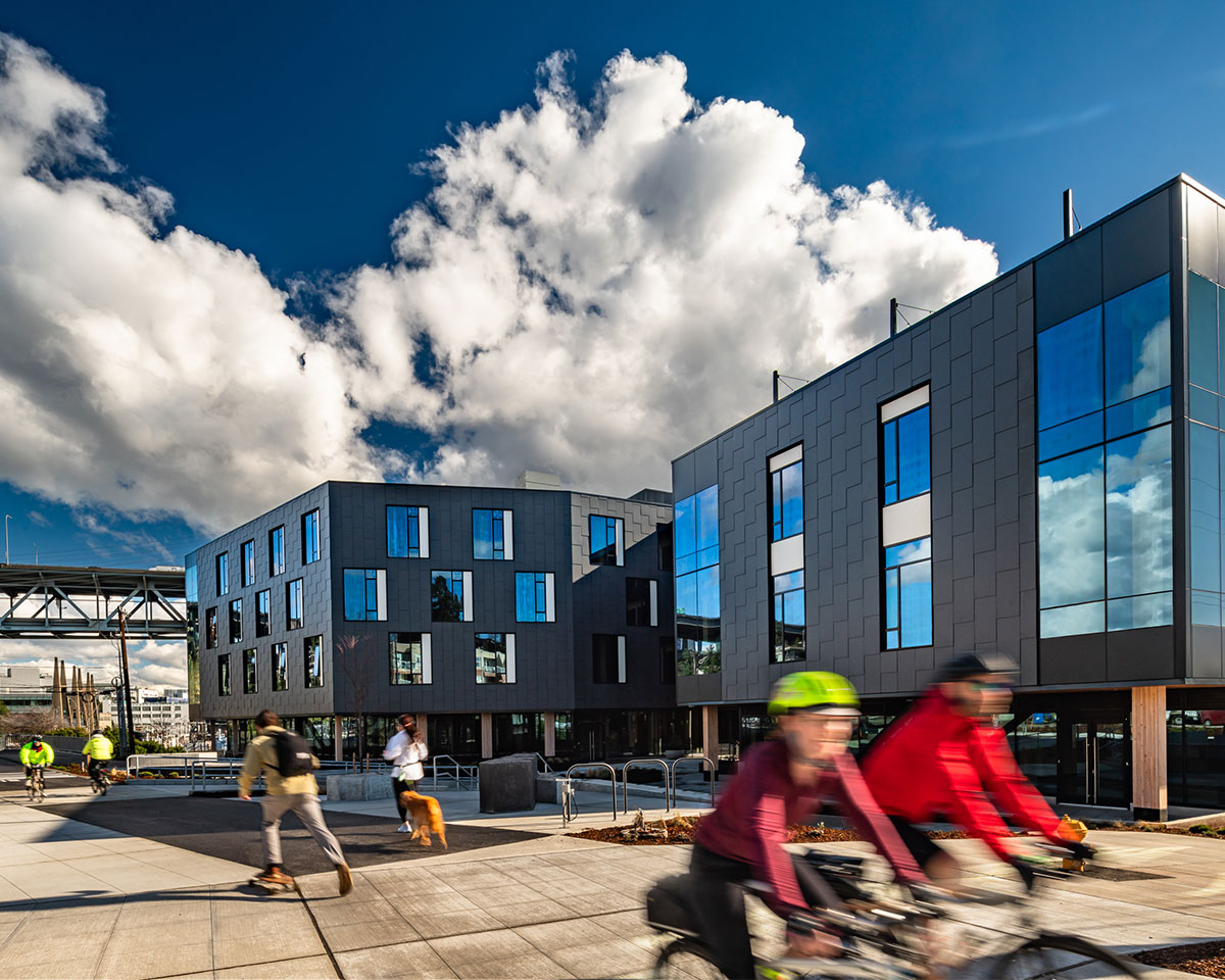 Photo of cyclists riding on the burke gilman trail in front of northlake commons on a sunny day