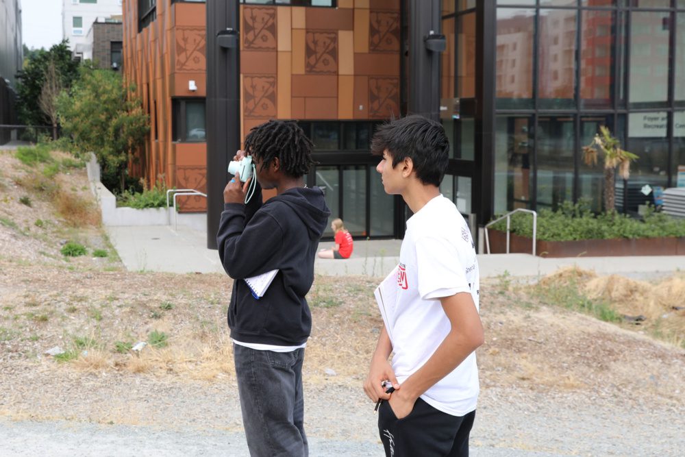 photo of students using their cameras to take a picture of the vacant lot next to orenda