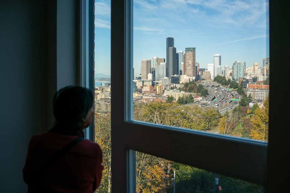 photo of a resident looking out the window from their uni overlooking downtown seattle