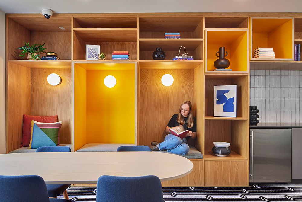 photo of a woman sitting in a reading nook reading a book surrounded by bright interior design